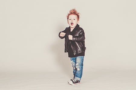 boy wearing black leather jacket and distressed blue denim jeans in room thumbnail