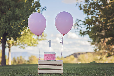 pink cake and balloons on wooden table during daytime thumbnail