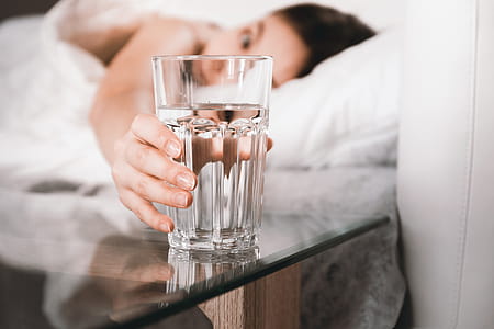 Close up Woman holding glass of water on bed in the morning thumbnail