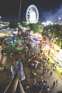 person wearing black-and-white Adidas supertstar near ferris wheel and people at night thumbnail