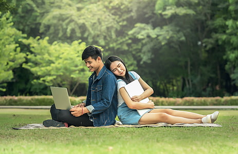 couples sitting on green brown textile on green grass field thumbnail