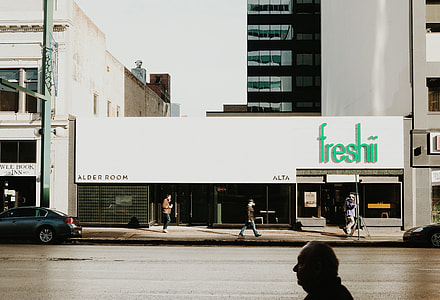 gray sedan park beside Freshii building during daytime thumbnail