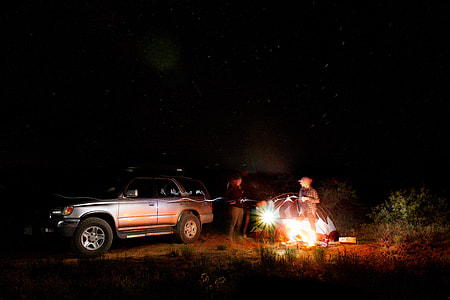 two person standing near car and black tent during night time thumbnail