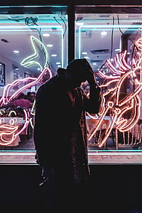 man standing in front of red and green neon signage thumbnail