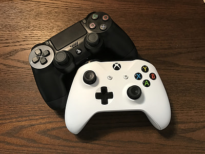 white Xbox and Sony PS4 controllers on brown surface thumbnail