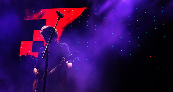 man playing guitar standing in front of microphone with stand thumbnail