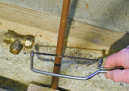 person cutting brown tube using hacksaw thumbnail