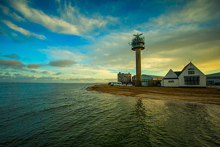 white and brown lighthouse beside sea thumbnail