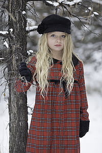 girl wearing red and white plaid coat holding tree branch thumbnail