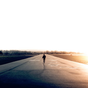 man standing on gray asphalt road near trees during daytime thumbnail