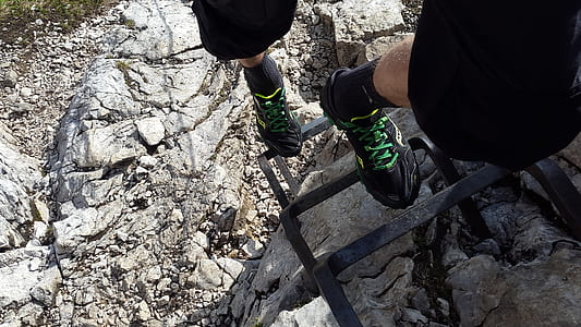 person on black steel ladder on mountain during daytime thumbnail