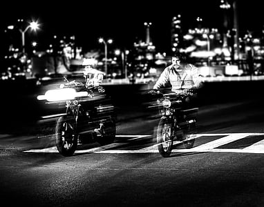 grayscale time-lapse photography of two men riding on motorcycle during nighttime thumbnail