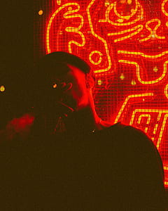 person puffing cigarette in front of red light fixture thumbnail