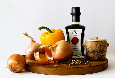 food photography of three red onions and yellow bell pepper on top of brown wooden chopping board thumbnail