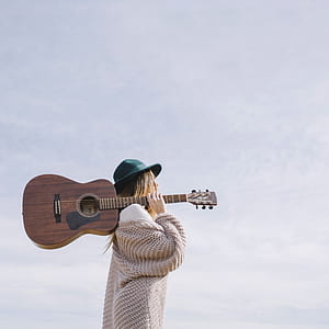 woman holding brown dreadnought acoustic guitar thumbnail