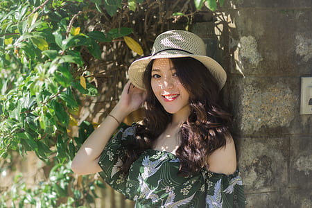 woman under green plant holding cap thumbnail
