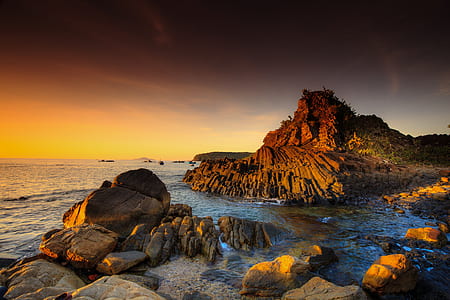 rock formation on body of water during sunset thumbnail