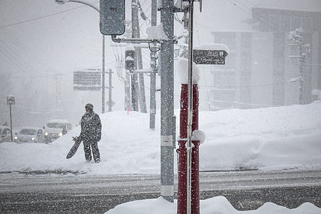 man holding snowboard standing on snow covered ground thumbnail