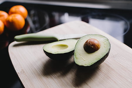 avocado fruit on chopping board beside green handled knife thumbnail