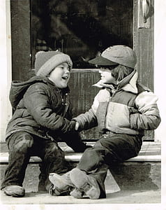 grayscale photo of two children sitting beside door thumbnail