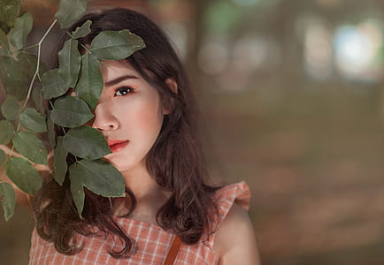 Woman Wearing Pink Sleeveless Top Behind Leaves thumbnail