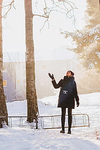 woman standing on snowfield beside tree thumbnail