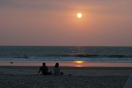 person sitting near body of water watching sunset thumbnail