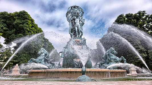 Blue Concrete Water Fountain Near Green Trees Under White Clouds thumbnail