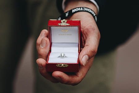 closeup photography of person holding clear gemstones silver-colored princess-cut ring in box thumbnail