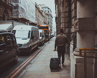 Man in Brown Jacket Holding Black Travel Luggage thumbnail
