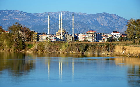 white concrete building surrounded with mountains near body of water at daytime thumbnail