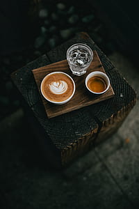 cappuccino near drinking glass on wooden table thumbnail