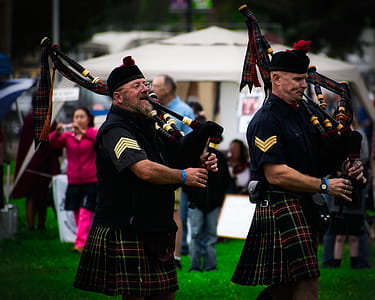 Two Men Playing Wind Instruments on Ground thumbnail