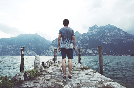 man standing on concrete dock in front of mountain during daytime thumbnail