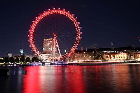 red lighted ferris wheel near calm body of water and buildings thumbnail