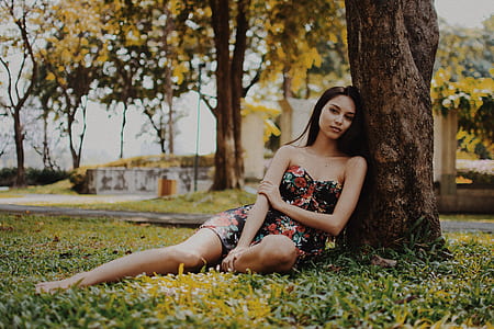woman leaning of tree wearing black and pink floral mini dress at daytime thumbnail