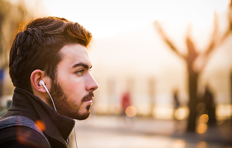 man wearing black turtleneck coat and earbuds selective-focus photography thumbnail