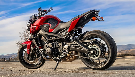 red and black sports bike parked on grey concrete pavement thumbnail