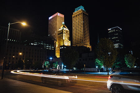 time-lapse photography of vehicle speeding on road near buildings at night thumbnail