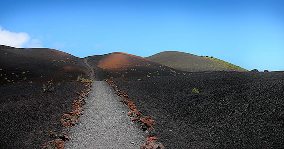 gray road between grass field near mountain thumbnail
