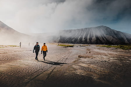 two man walking near mountain at daytime thumbnail