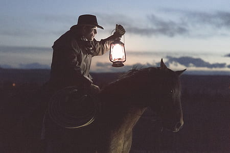 cowboy holding lantern riding on horse thumbnail