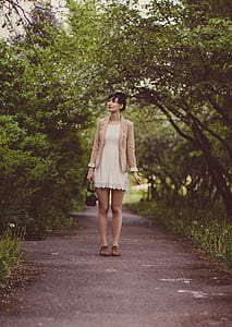 Woman in Beige Blazer Standing on Pathway Surrounded by Green Trees during Daytime thumbnail