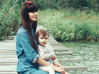 woman carrying child on her lap sitting on dock pier thumbnail