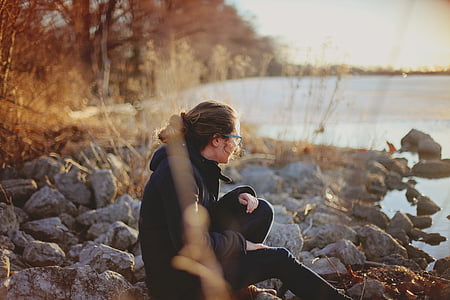 woman sitting on rock near body of water thumbnail