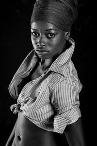 woman with black headdress and shirt standing on black background thumbnail