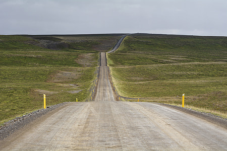 grey asphalt road in middle of grass field thumbnail