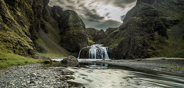 river connected to waterfalls surrounded by mountains under cloudy sky during daytime thumbnail