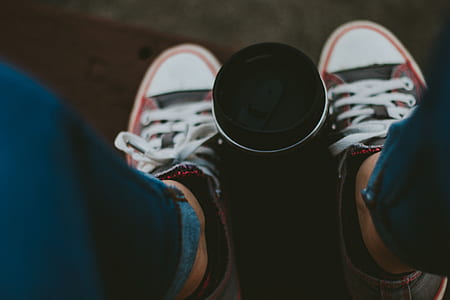 black tumbler between person's lace-up shoes thumbnail