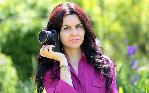 woman wearing purple dress shirt holding black DSLR camera thumbnail